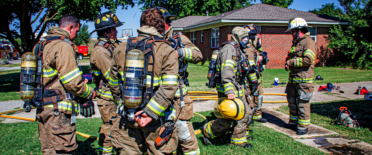 Firemen at scene of fire in a neighborhood.