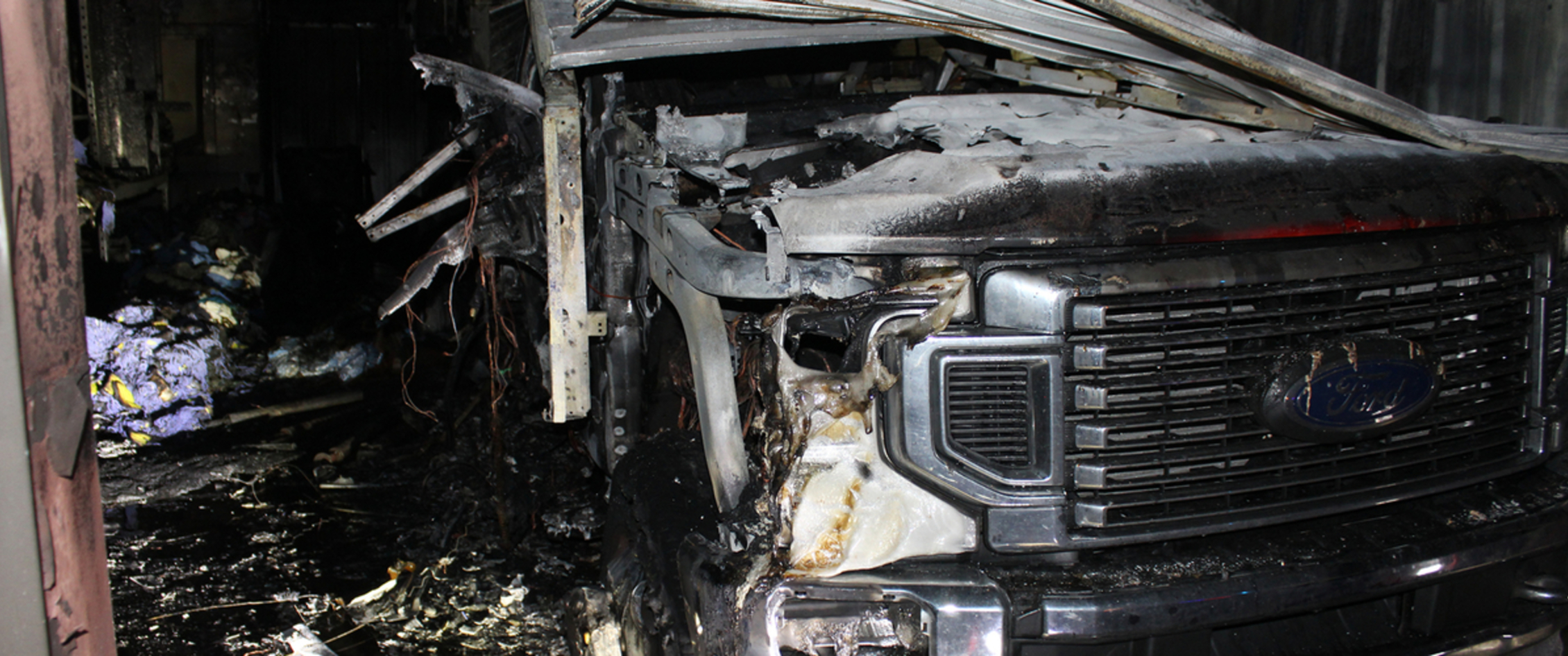 Scene of fire with burned vehicle.